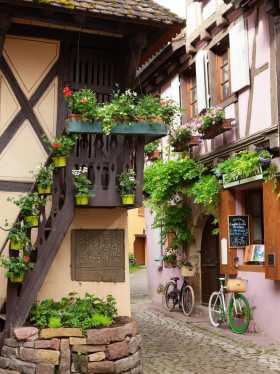 Fahrräder in einer elsässischen Fachwerkgasse mit blumengeschmückten Häusern