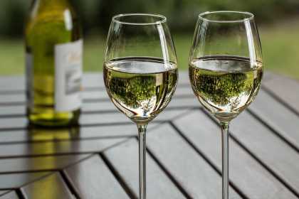 Zwei gefüllte Weißweingläser auf einem Tisch mit Flasche