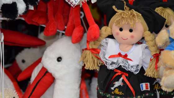 Elsass-Puppe in traditioneller Tracht neben einem Plüschstorch