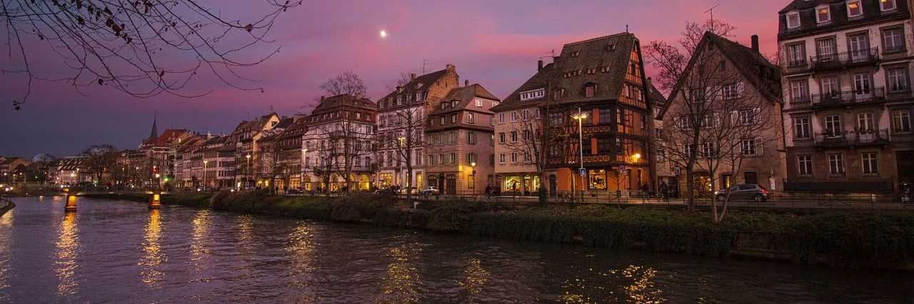 Historische Häuser am Kanal in Strasbourg bei Abendrot mit Spiegelungen und Mondlicht