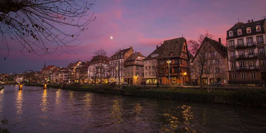 Historische Häuser am Kanal in Strasbourg bei Abendrot mit Spiegelungen und Mondlicht